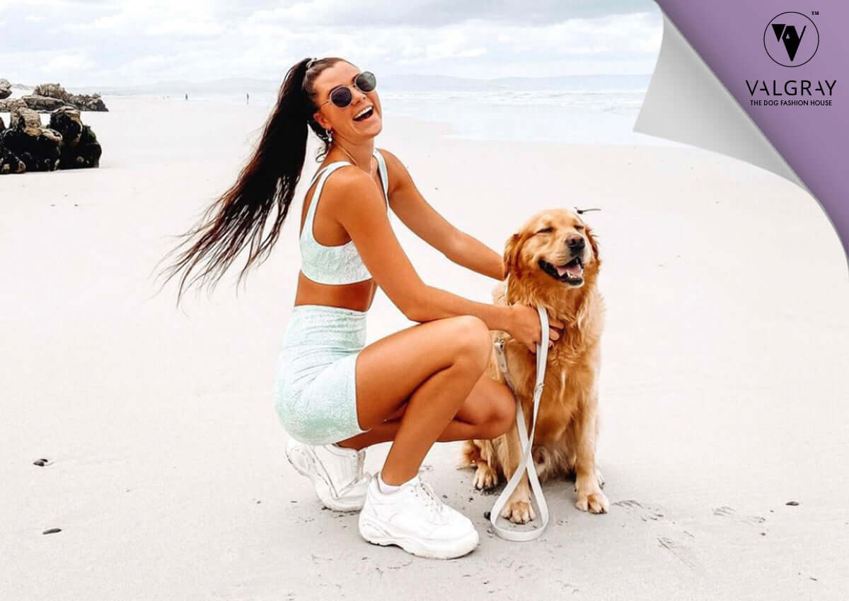 Valgray premium dog accessory blog image for 6 Ways to Spice Up Your Daily Dog Walks With Valgray Blog page. Blog image is a photograph of a young woman and her large-sized dog (Labrador dog) on the beach in an outdoor luxury lifestyle picture.